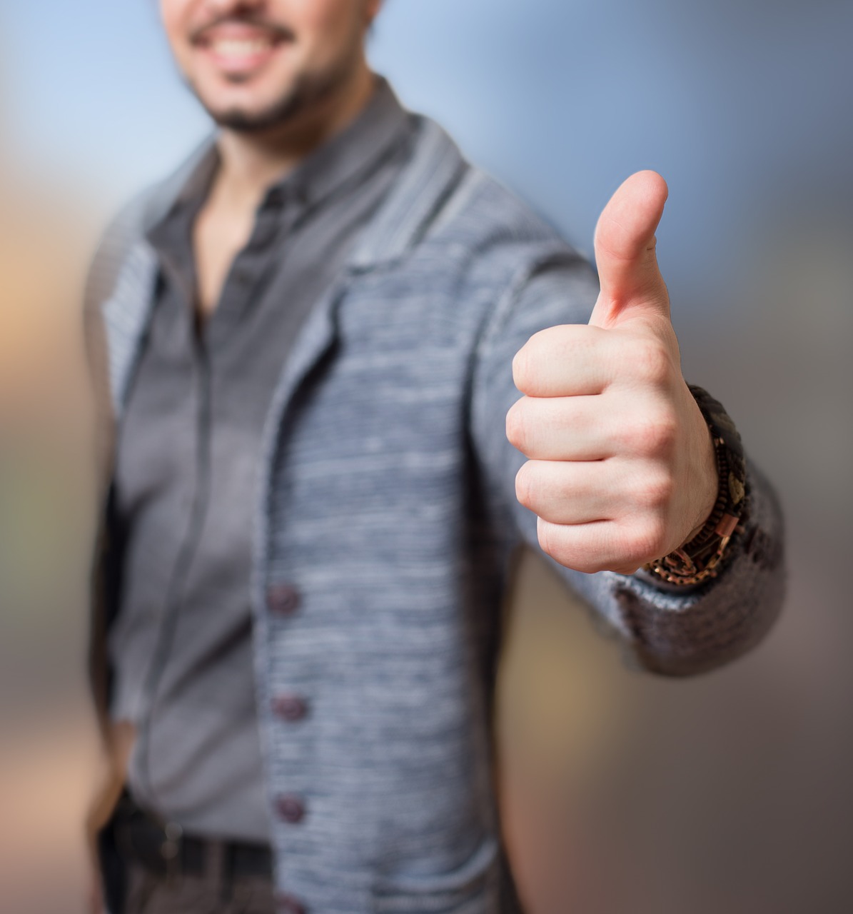 A man smiling, while giving a thumbs-up.